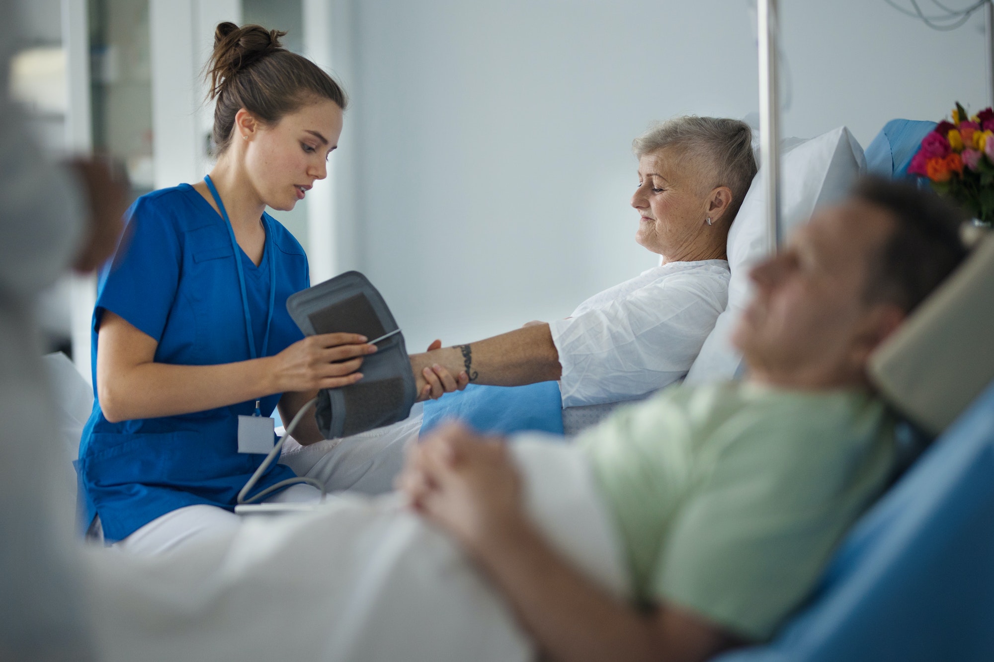 Young nurse chcecking blood presure to senior patient.